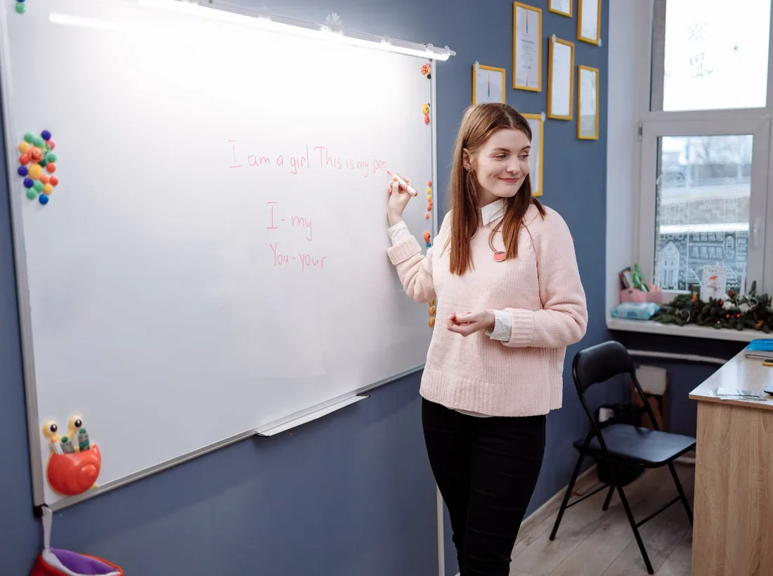 Lektorka vyučuje angličtinu pri bielej tabuli